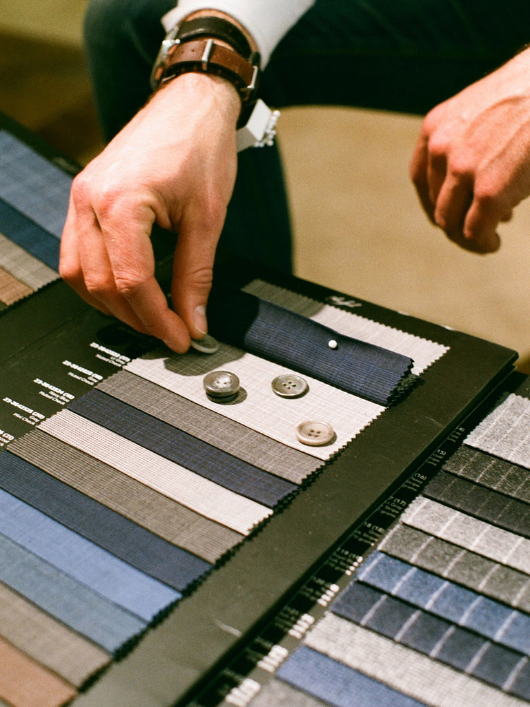 Tailor choosing buttons to match a bespoke suit
