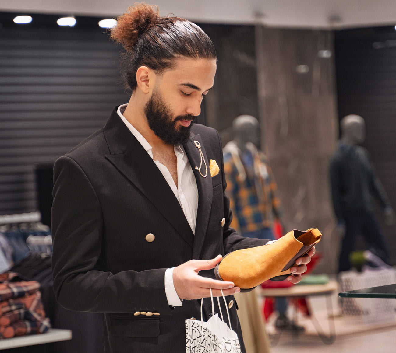 Man wearing a black suit and considering a light brown shoe