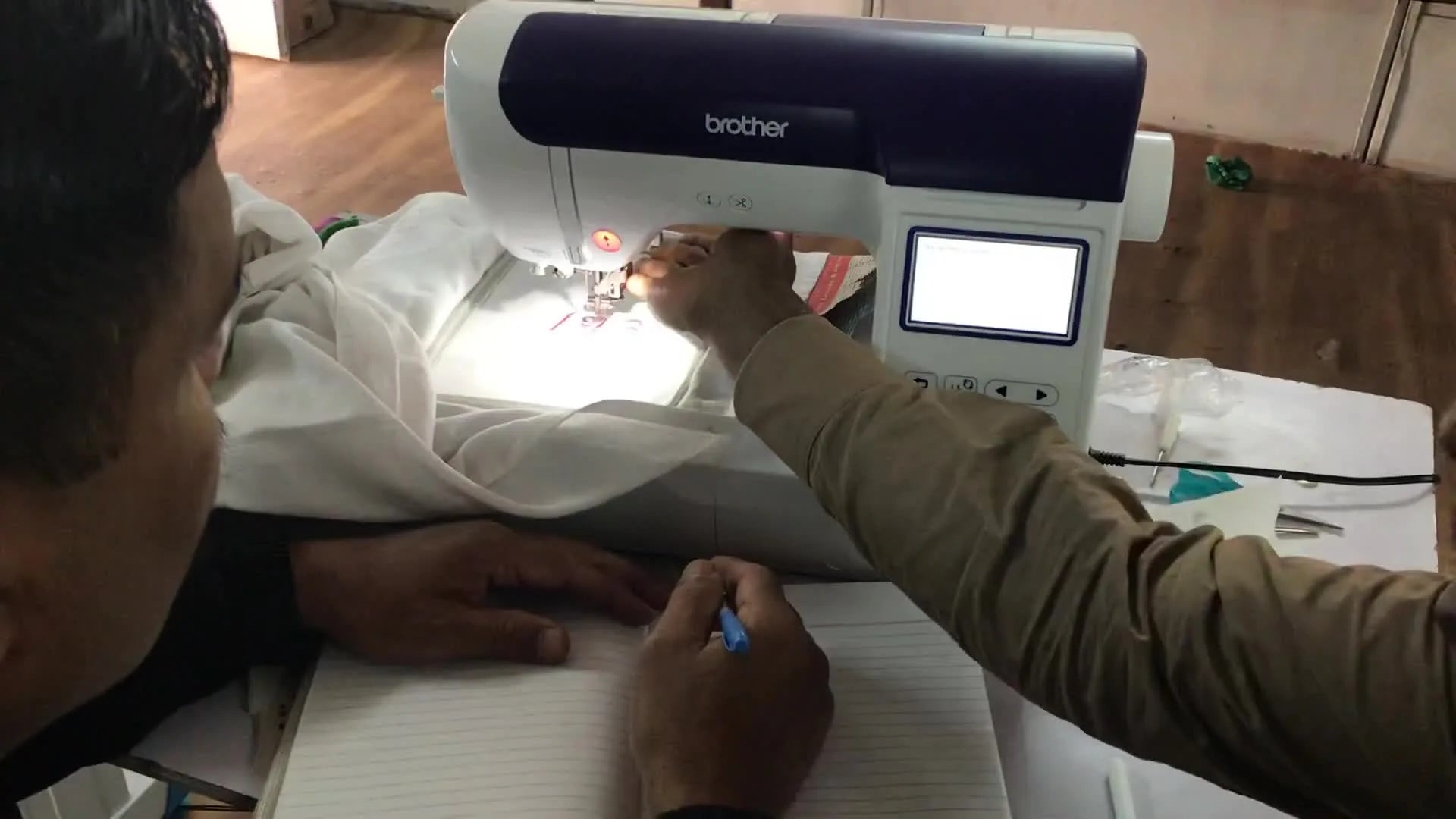 Close-up of a hand manually raising the presser foot of the embroidery machine.