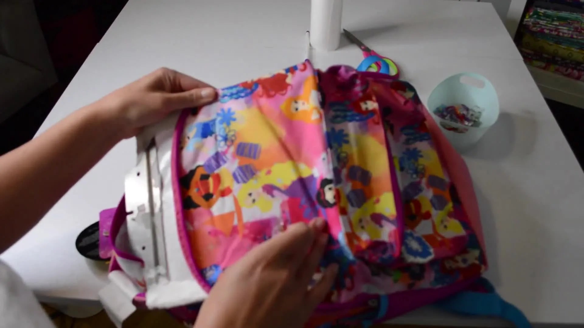 Hands using wonder clips to secure a backpack to a fast frame with sticky stabilizer.