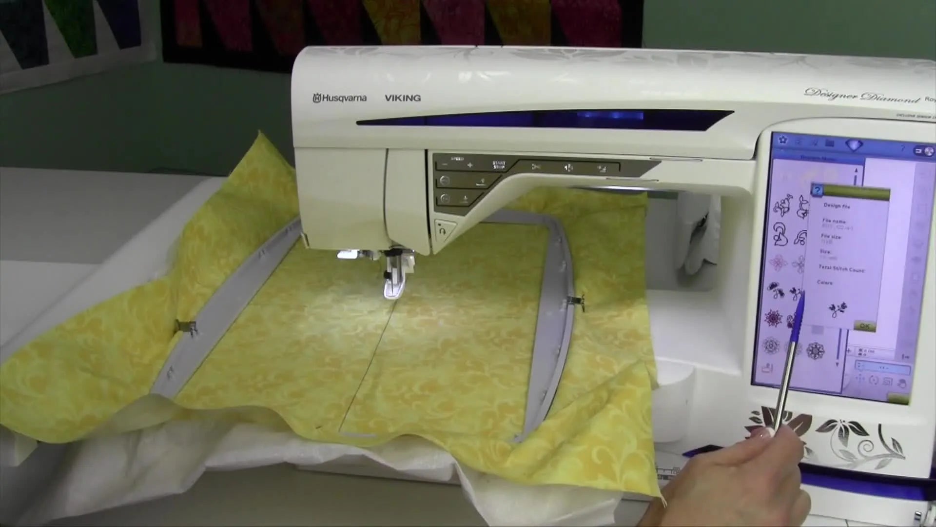 A stylus touching a design on the screen to bring up its information pop-up window.