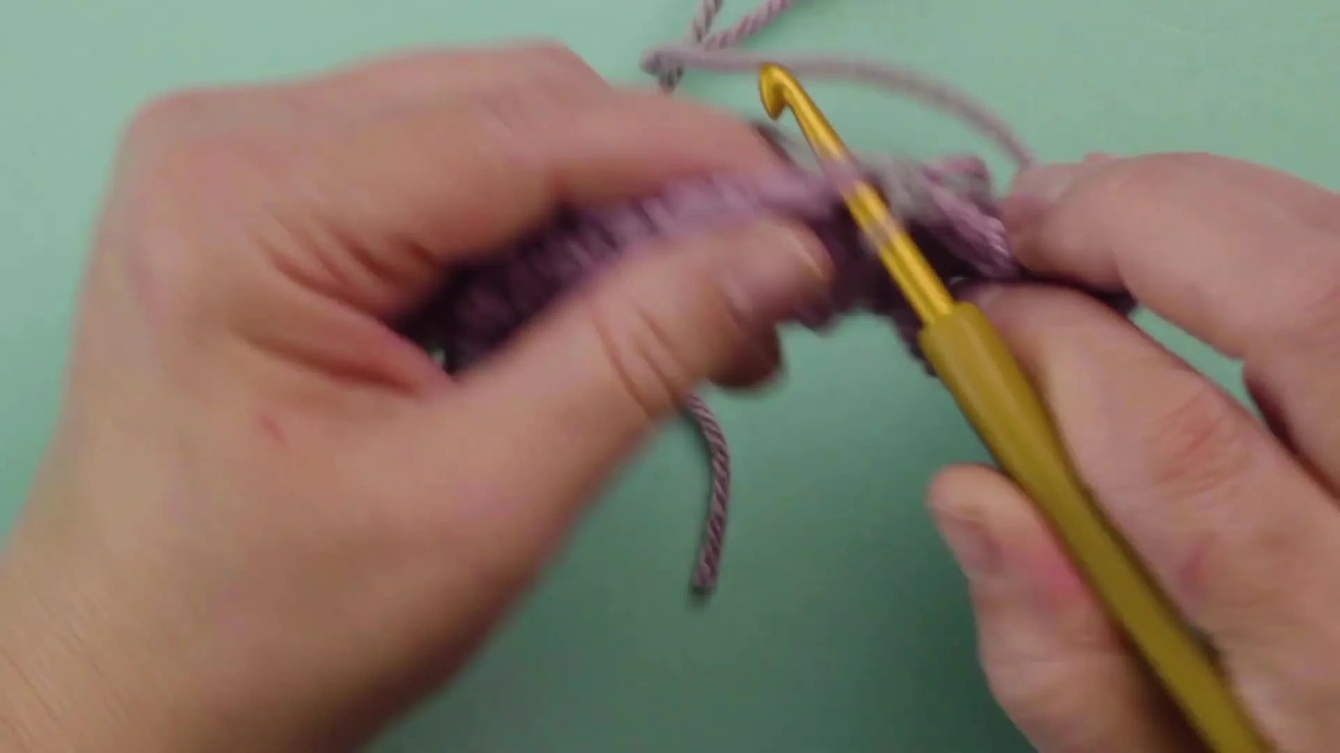 Hands crocheting multiple stitches using the new grey yarn after a successful color change.