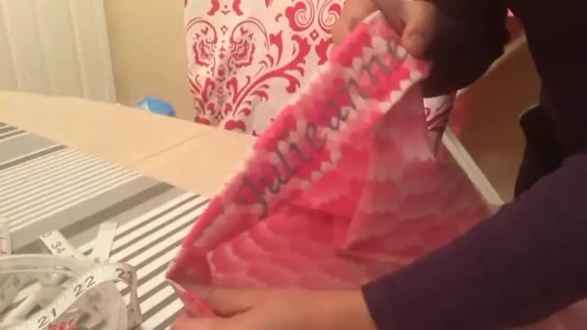 Patterned fabric strip with 'Julieanne' embroidered on it, folded on an ironing board.