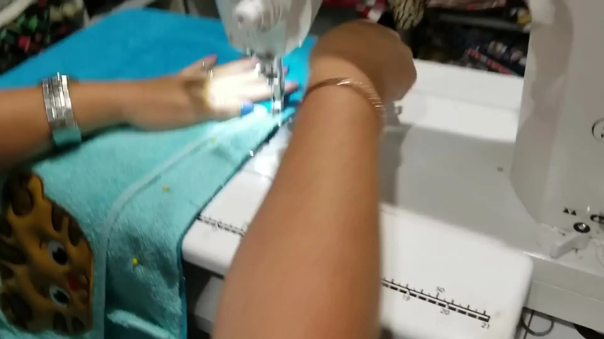 Hands guiding the pinned hood and towel under the sewing machine