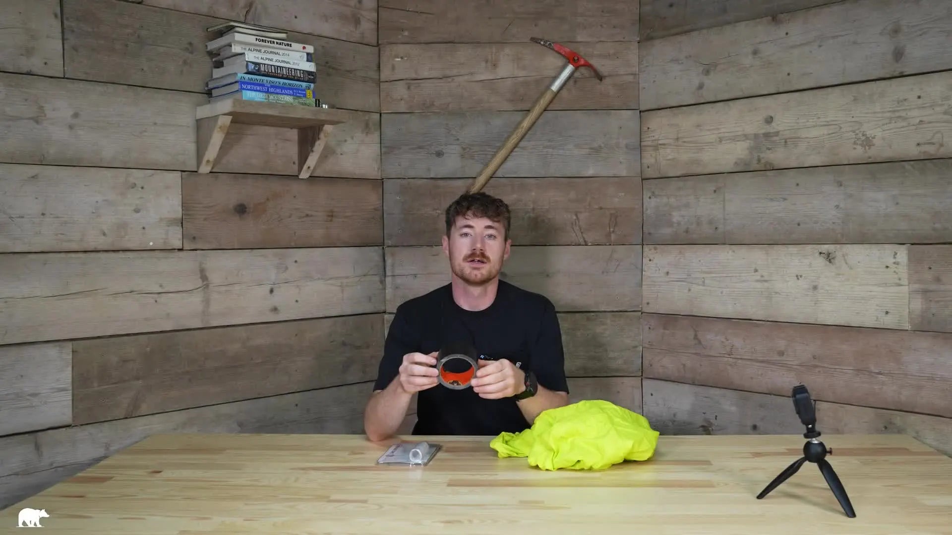 Man holding two rolls of tape, yellow jacket on table