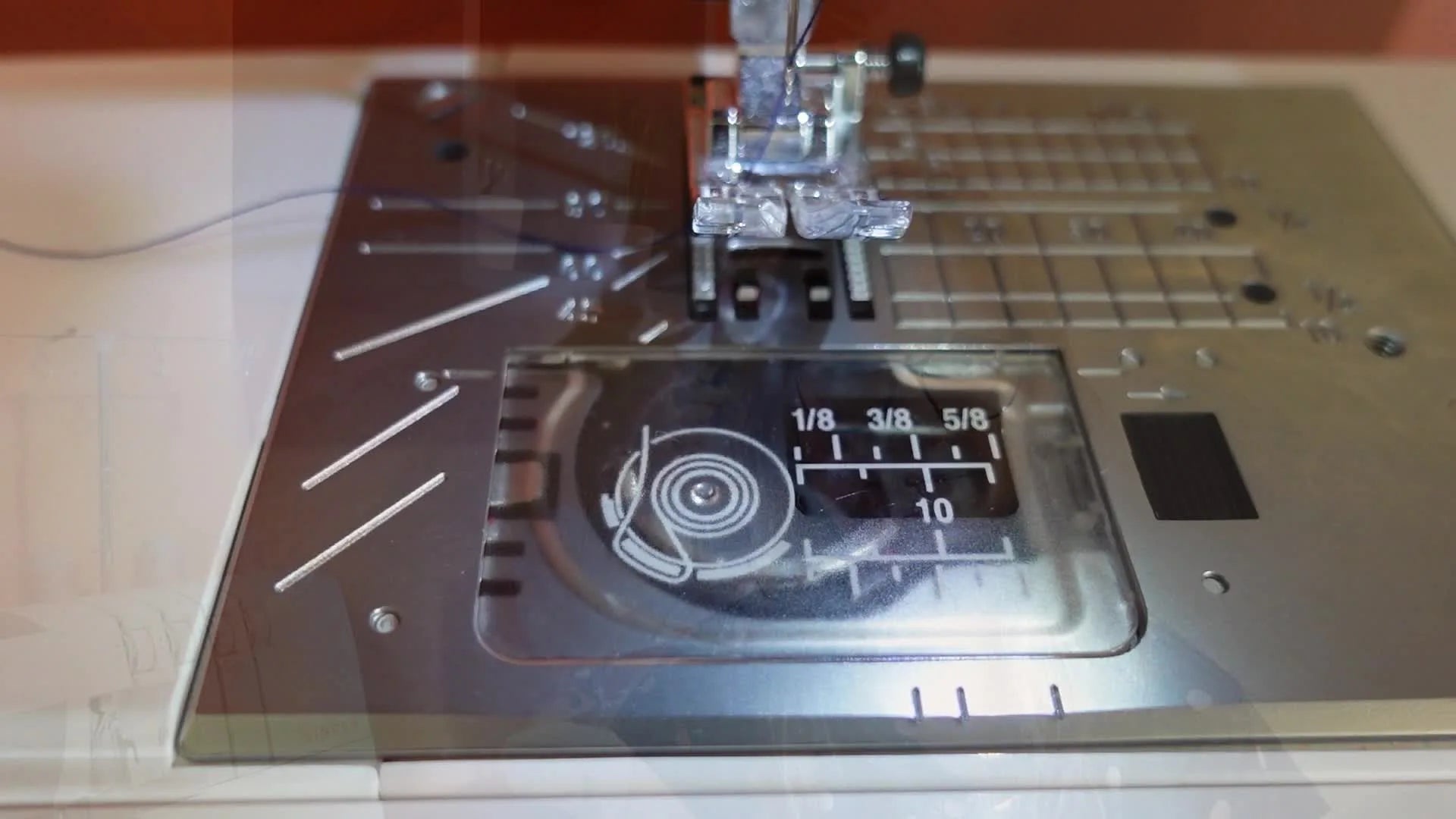 Close-up of a Janome 360 DC sewing machine's drop-in bobbin compartment.