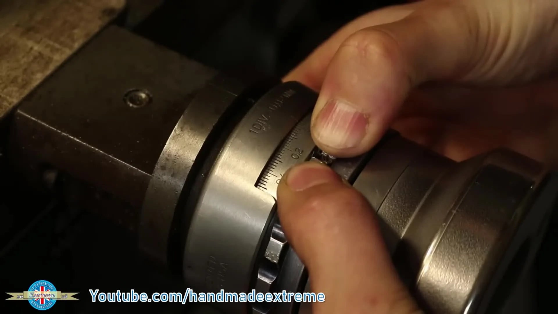 A close-up of a hand zeroing and locking the X-axis dial on the lathe, setting the datum for depth of cut