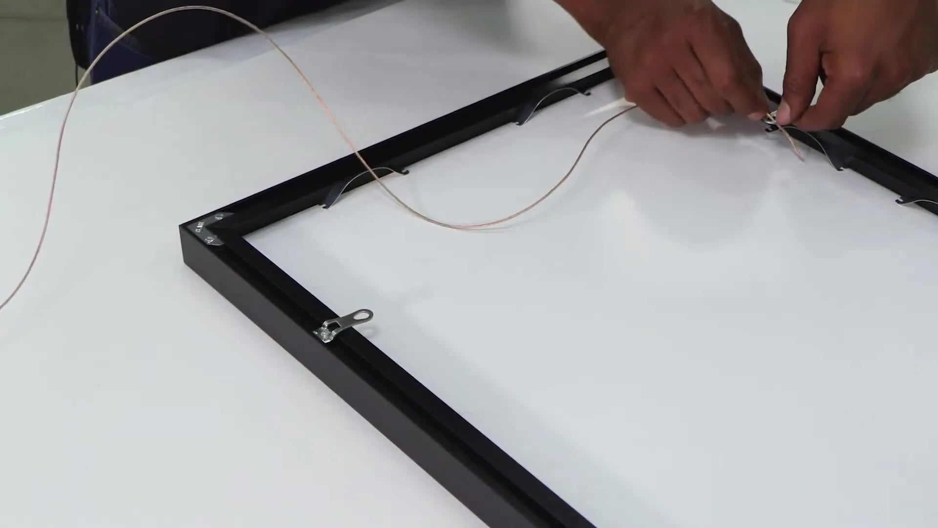 Hand applying a small bumper to the bottom corner of the frame.