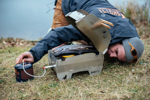 Junger Mann räuchert outdoor auf dem mobilen Skotti Grill