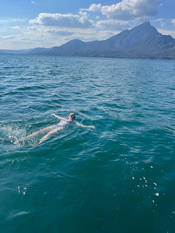 Junge Frau genießt ein Bad im Gardasee vor malerischer Kulisse