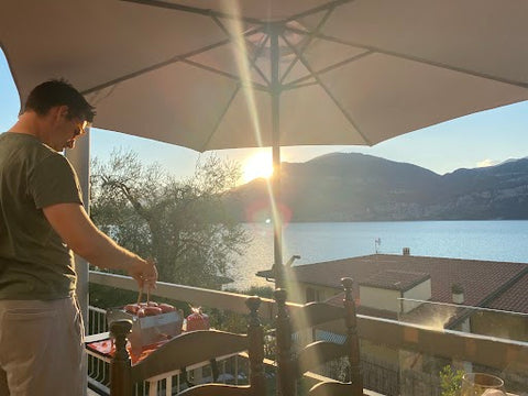 Junger Mann grillt mit dem Outdoor Skotti Grill im Sonnenuntergang am Gardasee