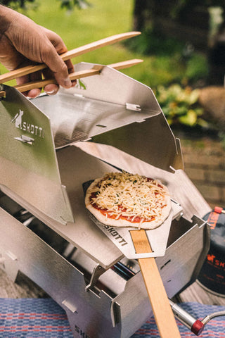 Pizza wird mit Pizzaschaufel SKOTTO Flip auf Pizzastein gelegt