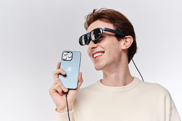 a man wearing Rokid Max glasses for sale and holding his iPhone