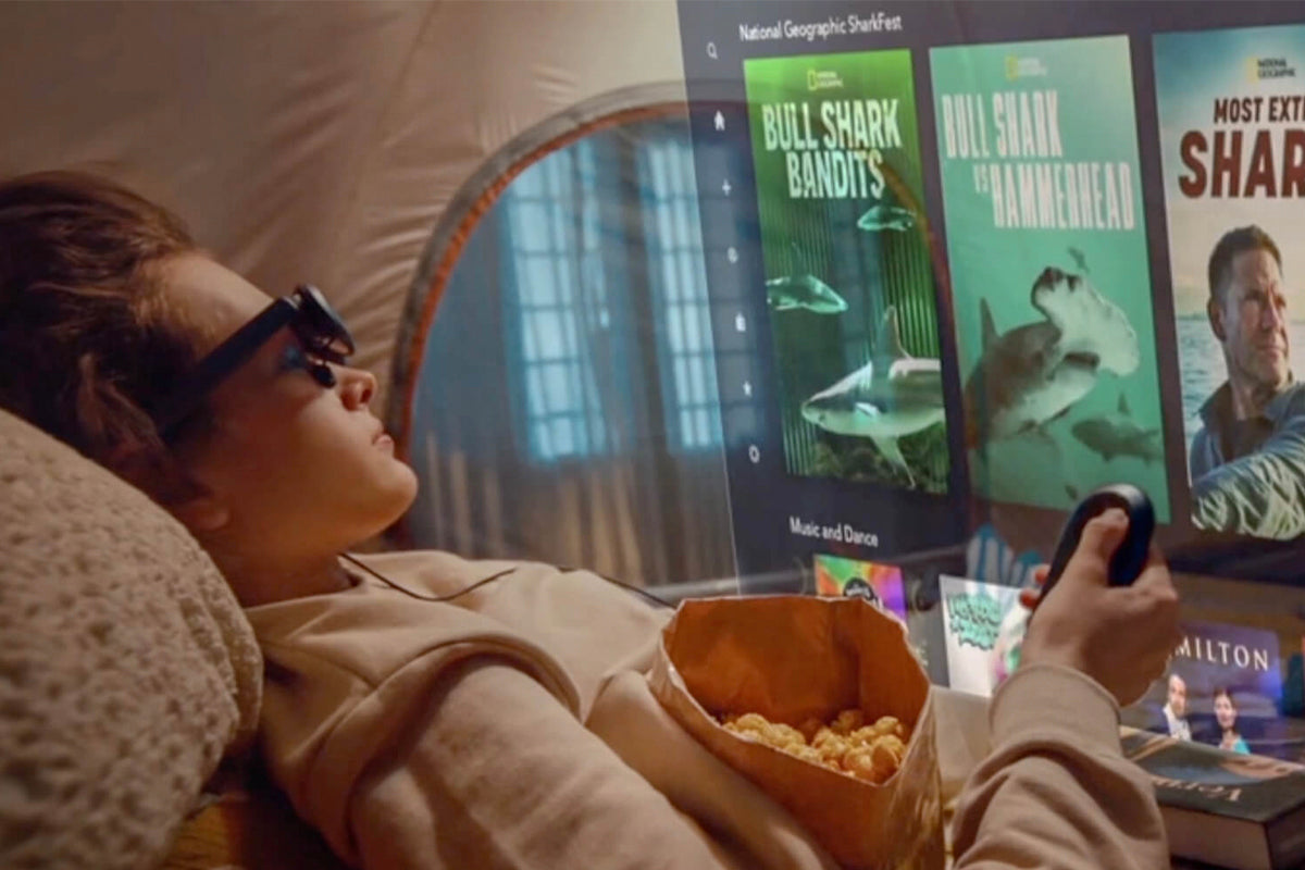 A woman lying on the bed using Rokid video display glasses