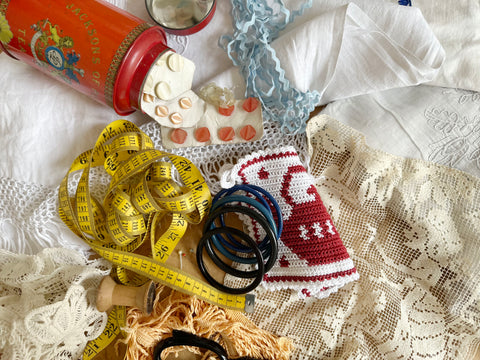 Fabrics, ribbons and buttons laying on a table with a measuring tape.