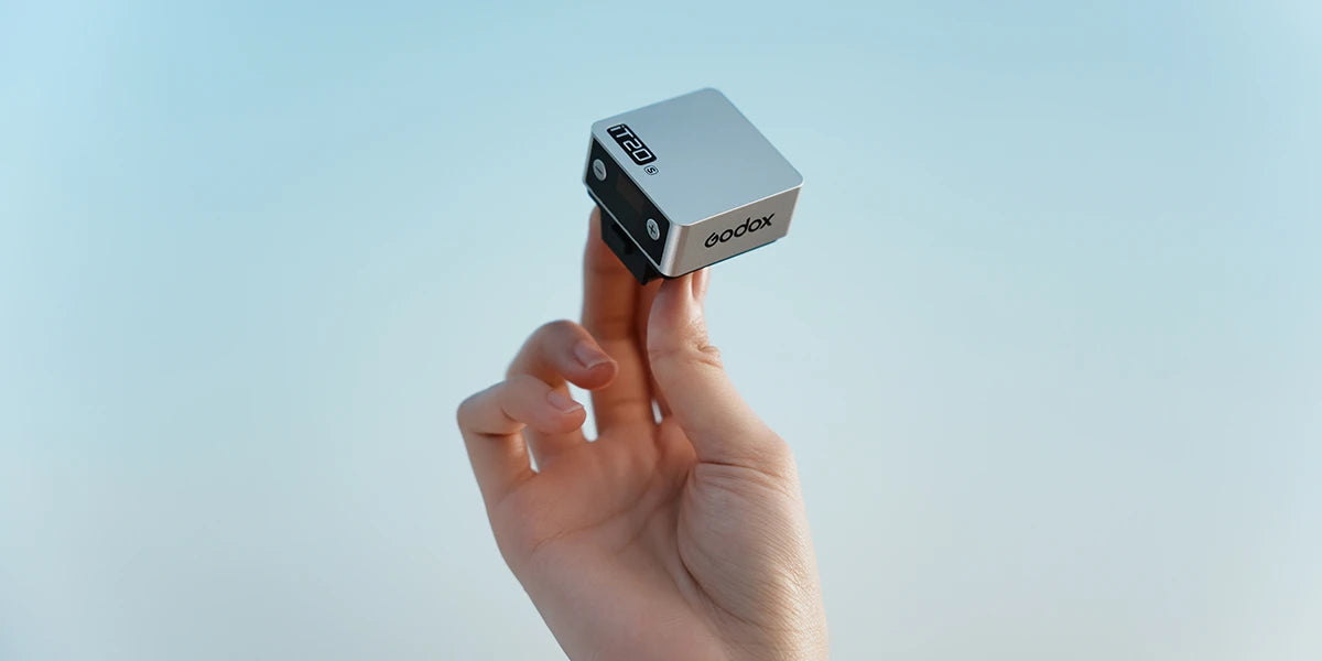 the Godox iT20 being held between a person's fingers to show how small it is