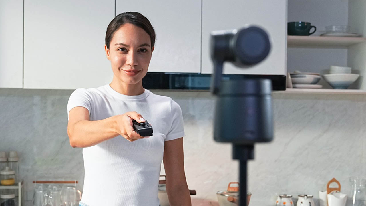 Woman using OBSBOT Tai Air Smart remote to control a Tail Air Streaming Camera