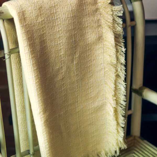 folded yellow pale throw blanket over a chair