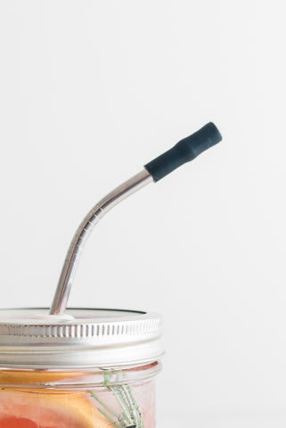 bent reusable stainless steel straw with black silicone tip on a mason jar tumbler filled with pink lemonade