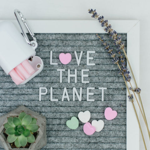 grey letter board that says love the planet with a lavender sprig, succulent and reusable straw