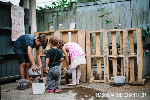 A group of kids creating potions in ice cream buckets at a diy potions shop set up for a Harry Potter themed birthday party