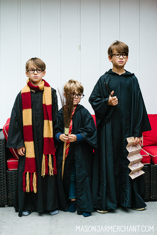 three boys dressed up as Harry Potter wearing DIY Hogwart's cloaks sewn from thrifted black flat sheets