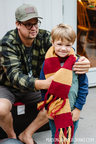 smiling boy wearing a scarlet and yellow hand crocheted Gryffindor House Hogwart's scarf