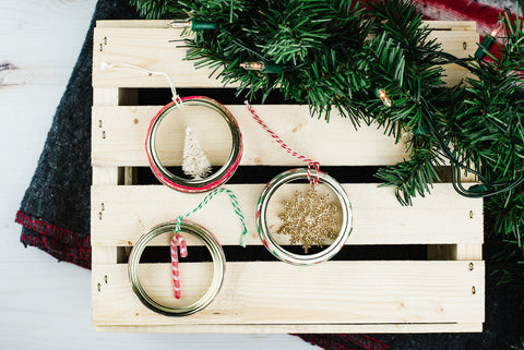 three handmade miniature ornament mason jar ring ornaments on a wooden crate