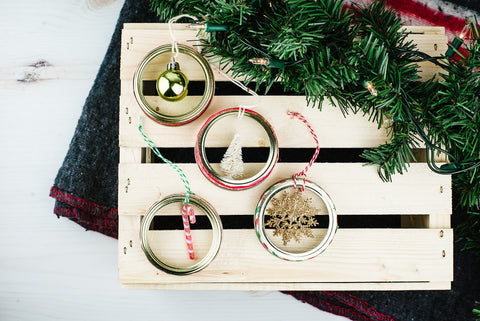 set of four DIY mason jar ring ornaments with small Christmas embellishments in the centre