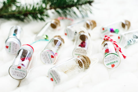 small bottle ornaments with made in Canada stickers on the bottom laying on a large white knit backdrop