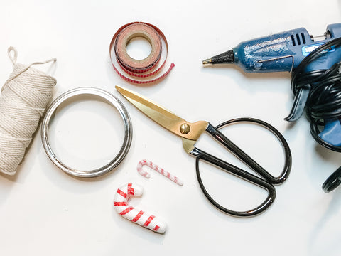 hot glue gun, scissors, twine, washi tape, miniature red and white striped candy canes and a mason jar flat lid