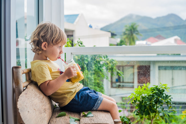 boy in a yellow tshirt and jean shorts drinking a smoothie from a mason jar