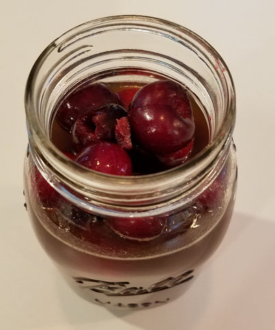 Jar of bourbon soaked cherries in a Ball mason jar