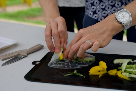 Photograph of a person's hands as they assemble a Vietnamese rice roll with vegetables and herbs directly from the City Sprouts farm.