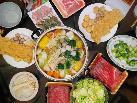 A top-down photograph of hotpot soup and ingredients, a dish traditionally eaten at reunion dinner during the Lunar New Year.