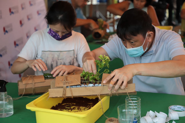 Two people at a City Sprouts planter-making workshop, using recycled materials to create planters.