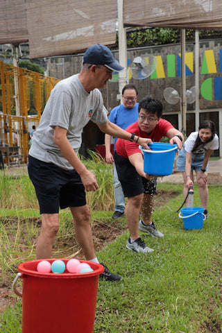 A team playing a bucket challenge at an Amazing Farm Race corporate bonding activity at City Sprouts.