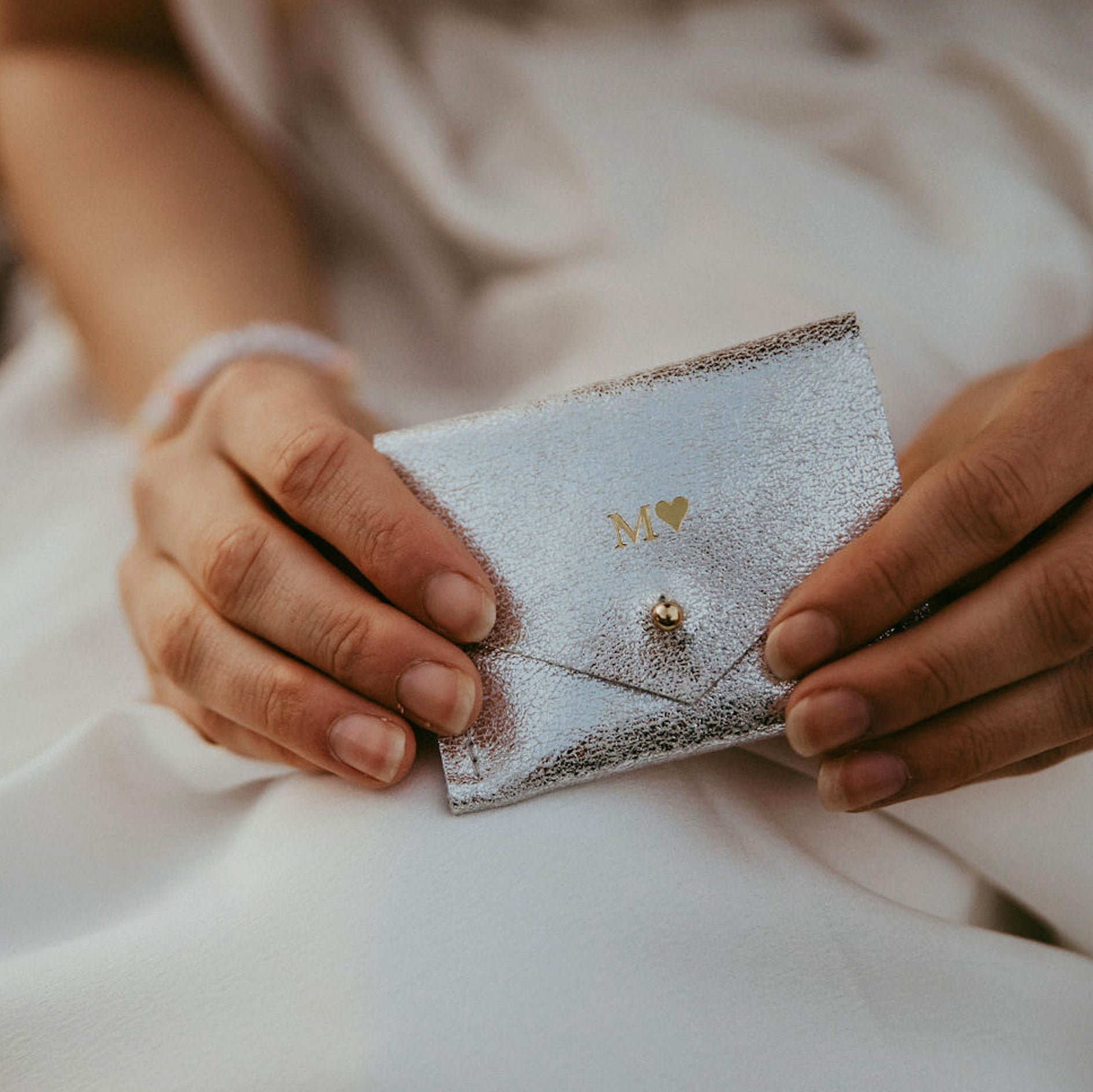 Personalised Silver Jewellery Pouch in the hands of bride, it holds her wedding bands.