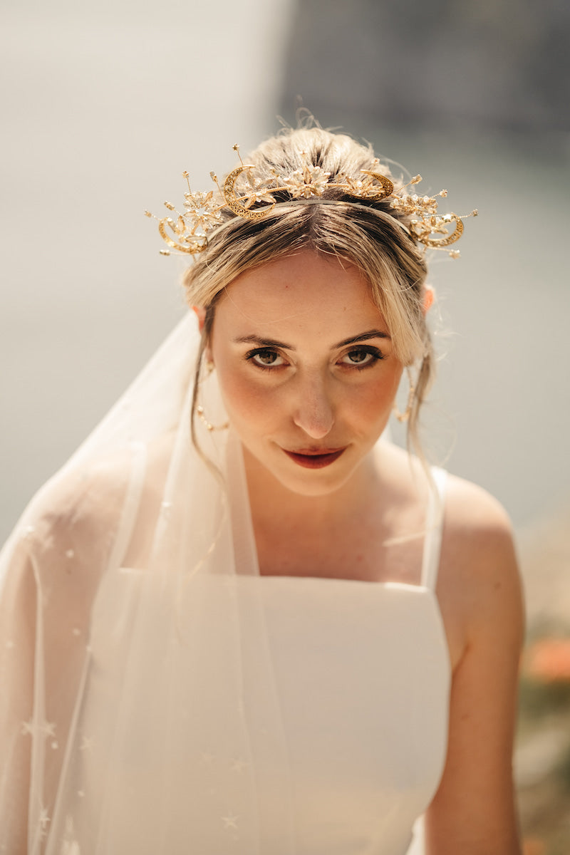 Bride wearing white strap dress with star veil and beautiful gold celestial headpiece.