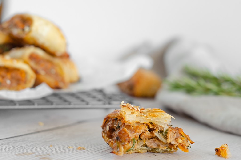 A gluten free sausage roll with a sneaky bite taken out of it