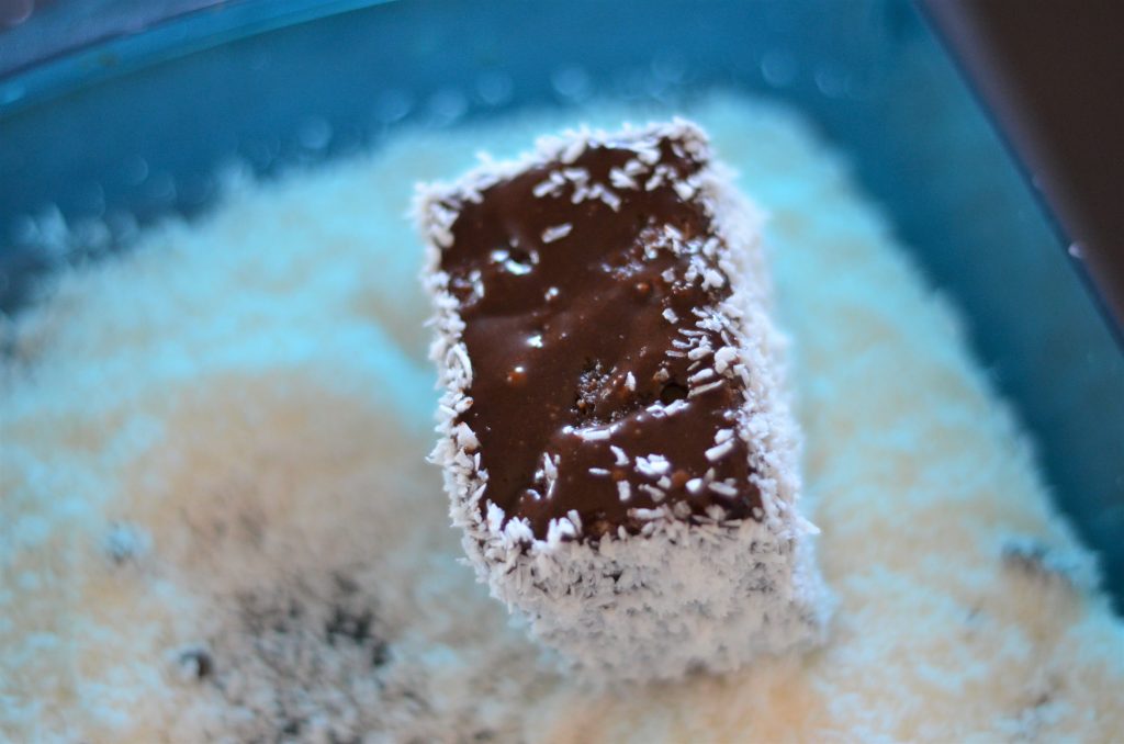 Covering the lamington in coconut