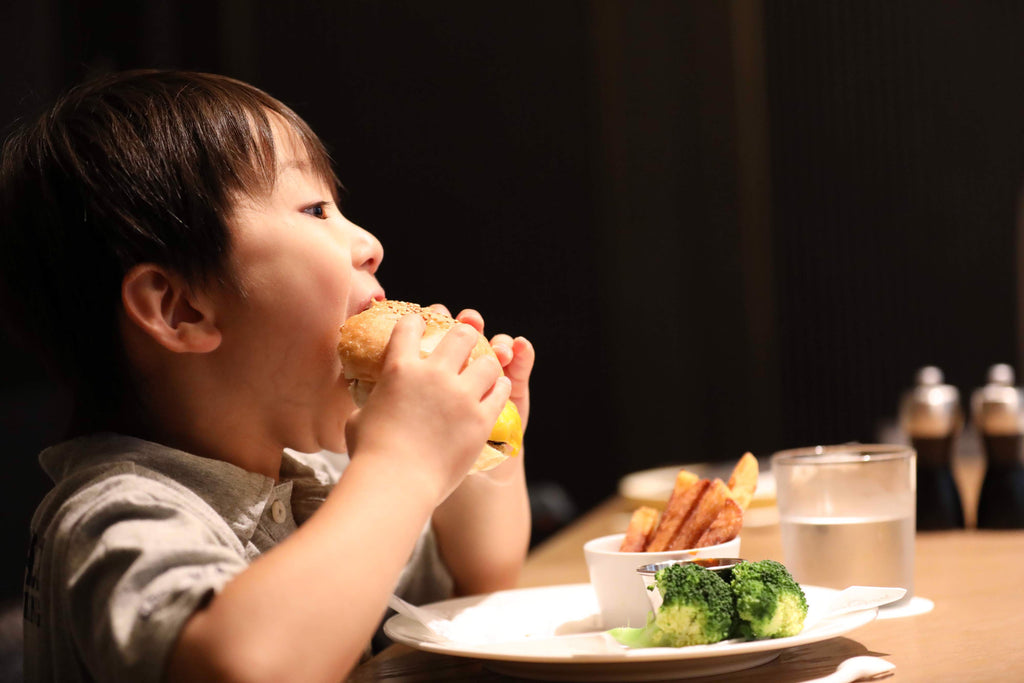 子供がハンバーガを食べている画像