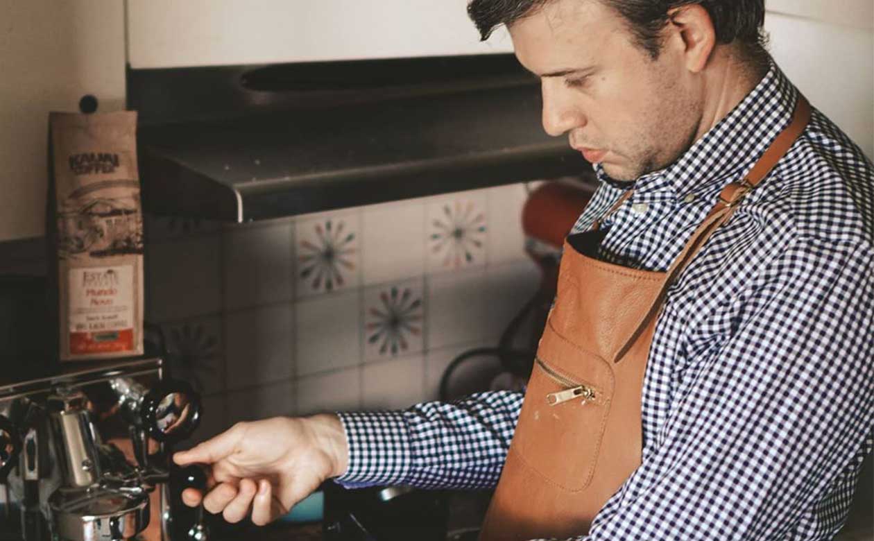 a young man makes kauai coffee at home with an espresso machine