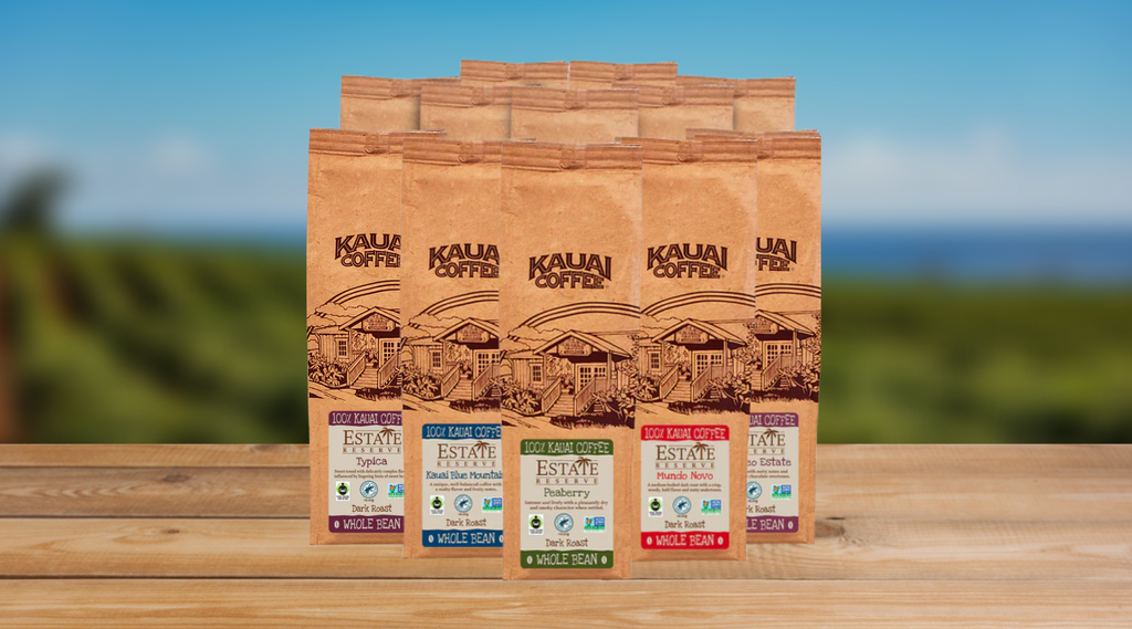 Kauai coffee estate reserve coffees sit on a wooden surface with a shallow depth of field image of the orchard in the background.