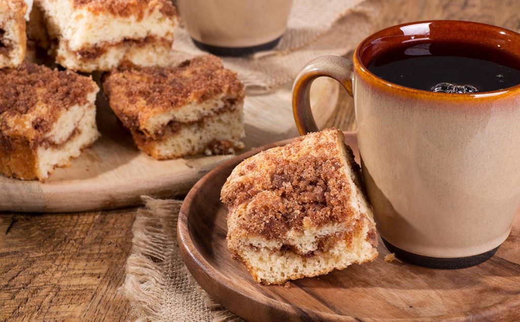 brewed kauai coffee in a brown mug with a piece of light coffee cake beside it