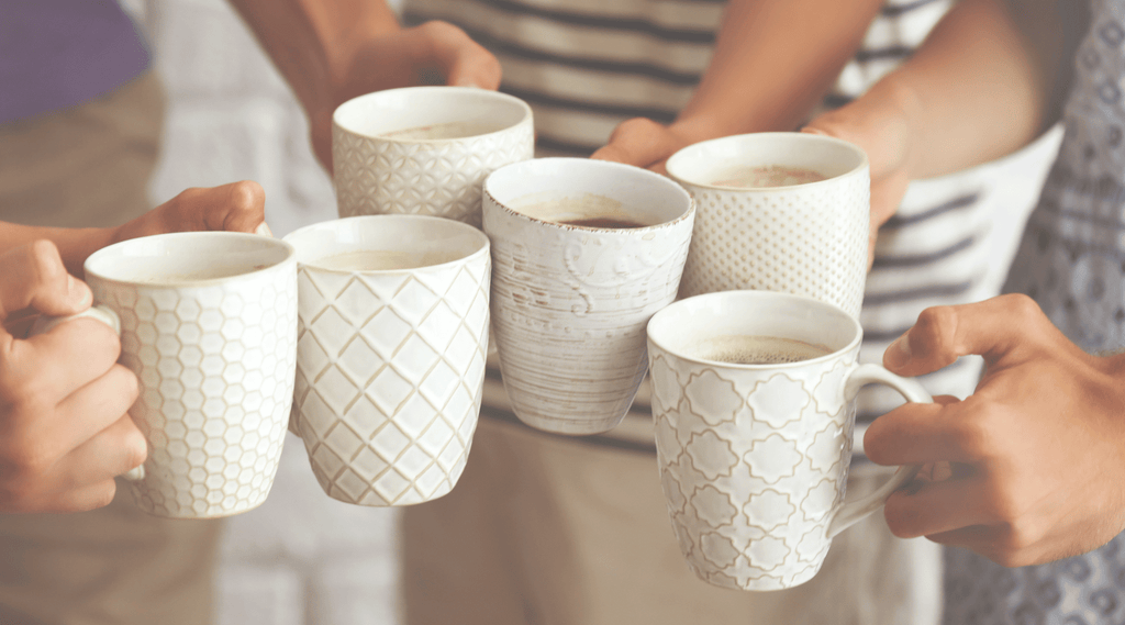 coffee tasting at home. four friends hold two mugs of coffee each