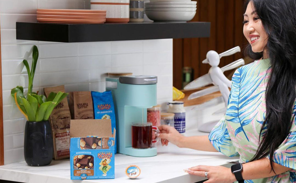 a woman makes a cup of Kauai coffee using an automatic brewer