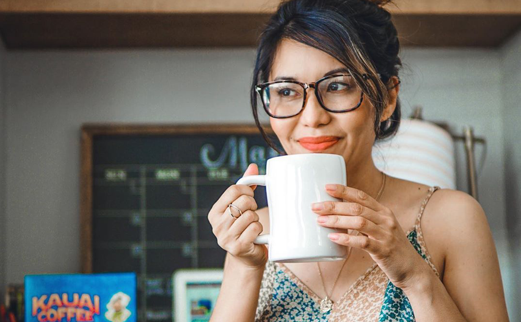 woman drinking kauai coffee from a white mug