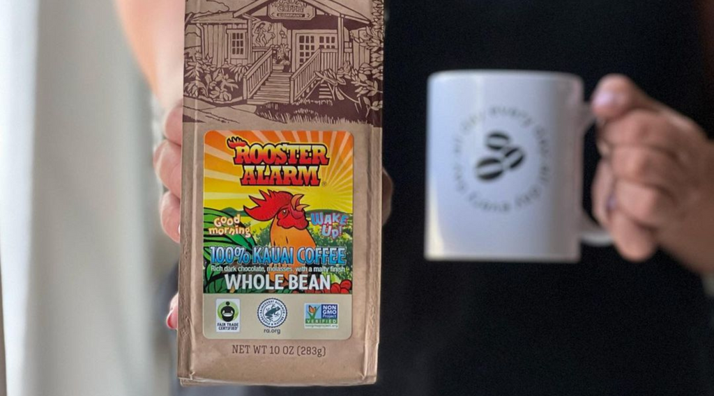 a woman holds a bag of kauai coffee rooster alarm coffee in one hand and a white mug in the other.