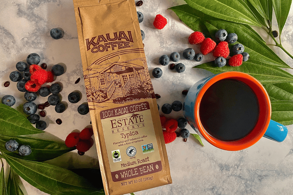 kauai coffee typica surrounded by fruit and coffee beans on a white counter top